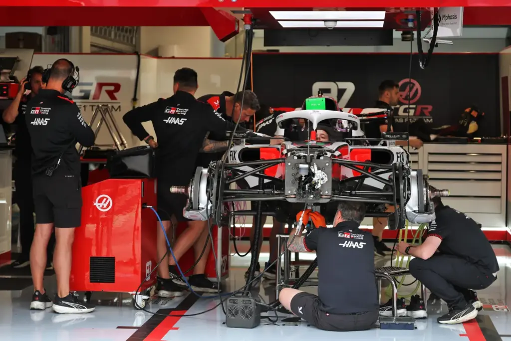 Haas F1 Team VF-26 being prepared by mechanics in the pit garage.